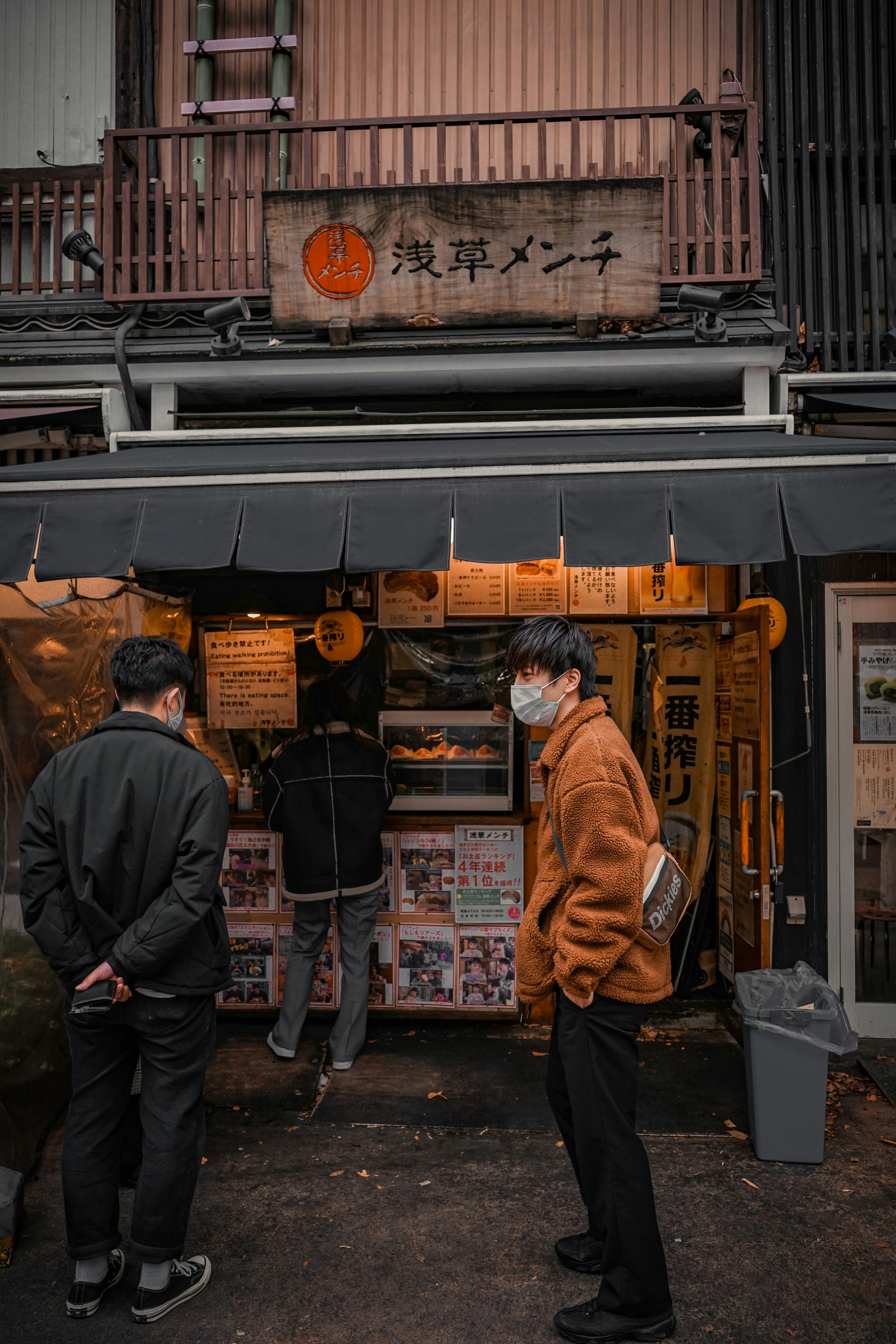 man in black jacket standing in front of store