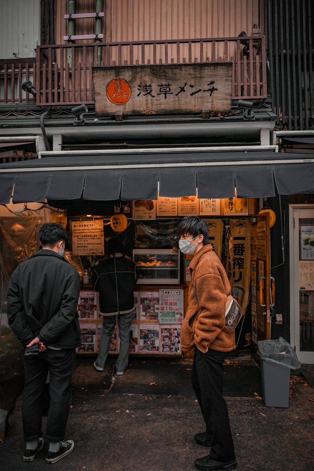 man in black jacket standing in front of store