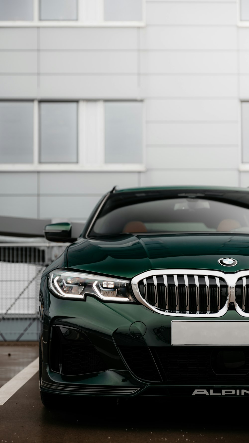 green mercedes benz coupe parked near white building during daytime