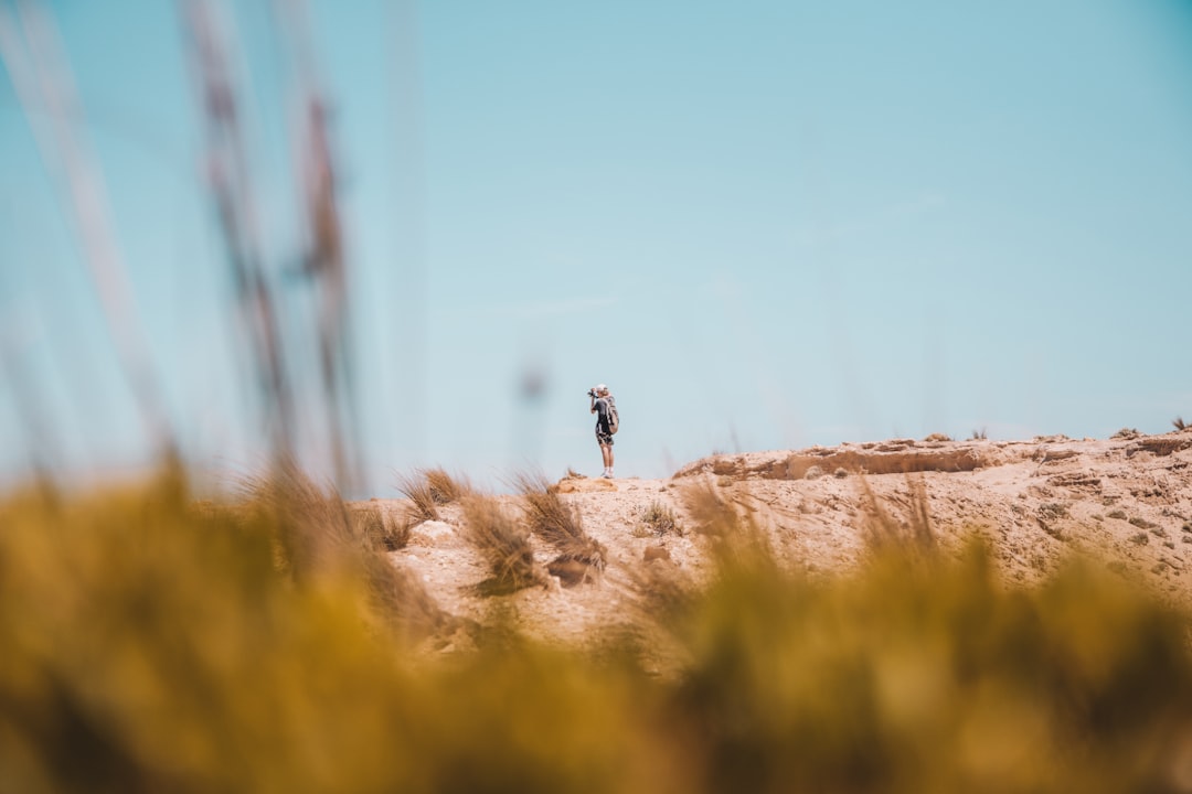 person in black jacket and pants standing on brown rock during daytime