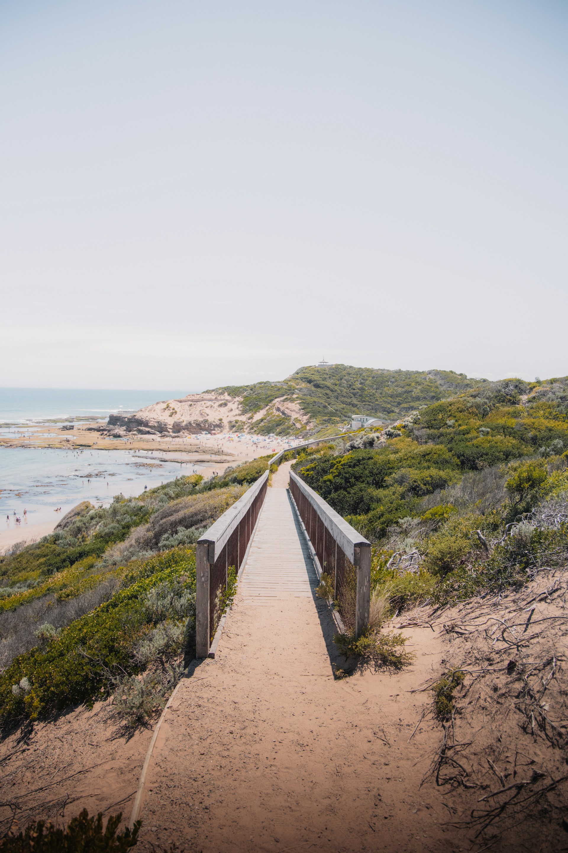 brown wooden pathway on brown sand near body of water during daytime
