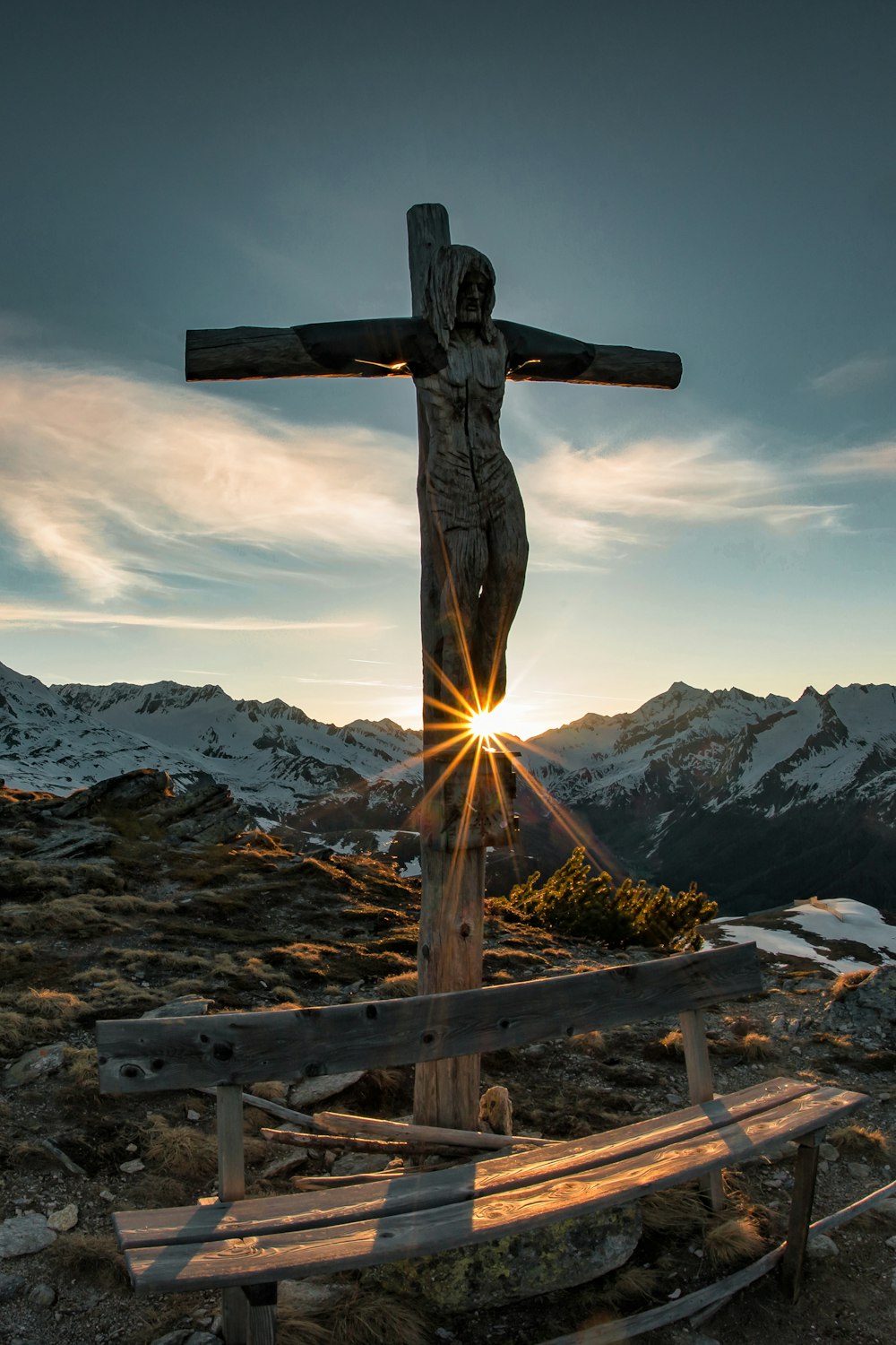 cruz de madeira marrom na cerca de madeira marrom perto da montanha coberta de neve durante o dia