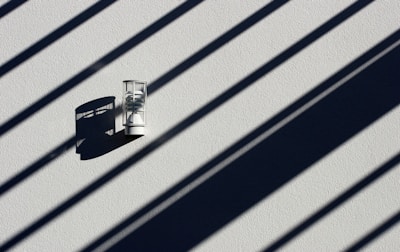 A matte black wall sconce illuminating a textured white wall with subtle elegance.
