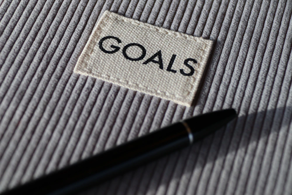 A notebook with the word goals beside a pen