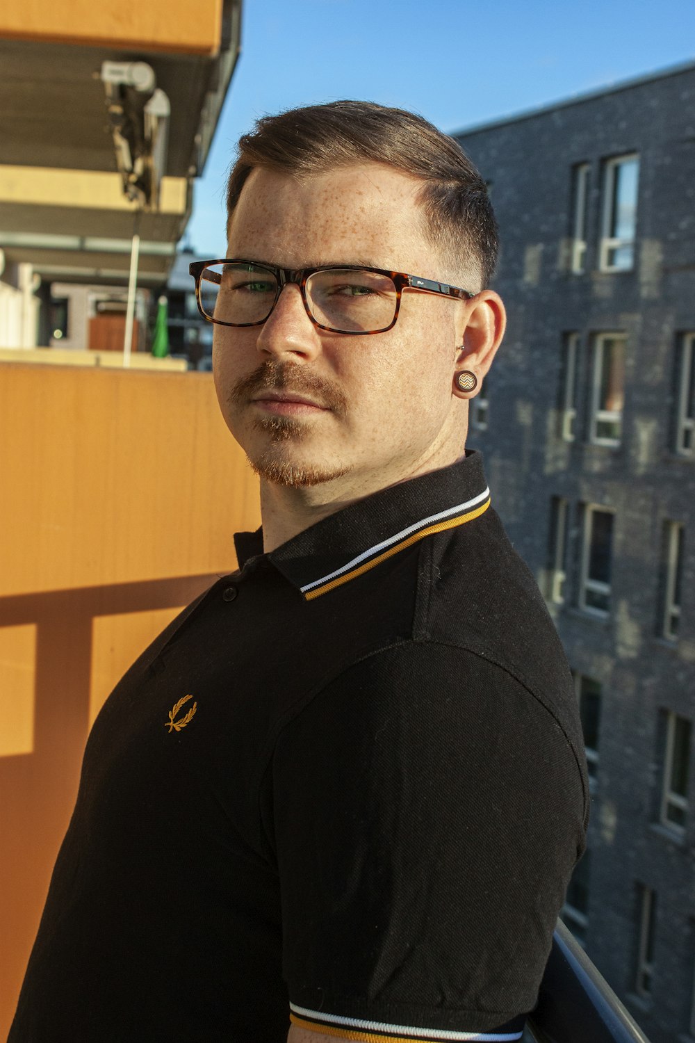 man in black and yellow polo shirt wearing black framed eyeglasses