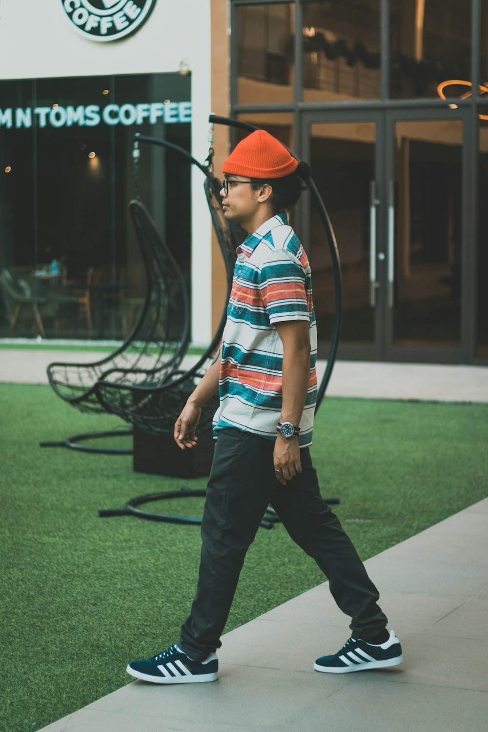 man in orange cap and blue white and red plaid dress shirt standing on green grass