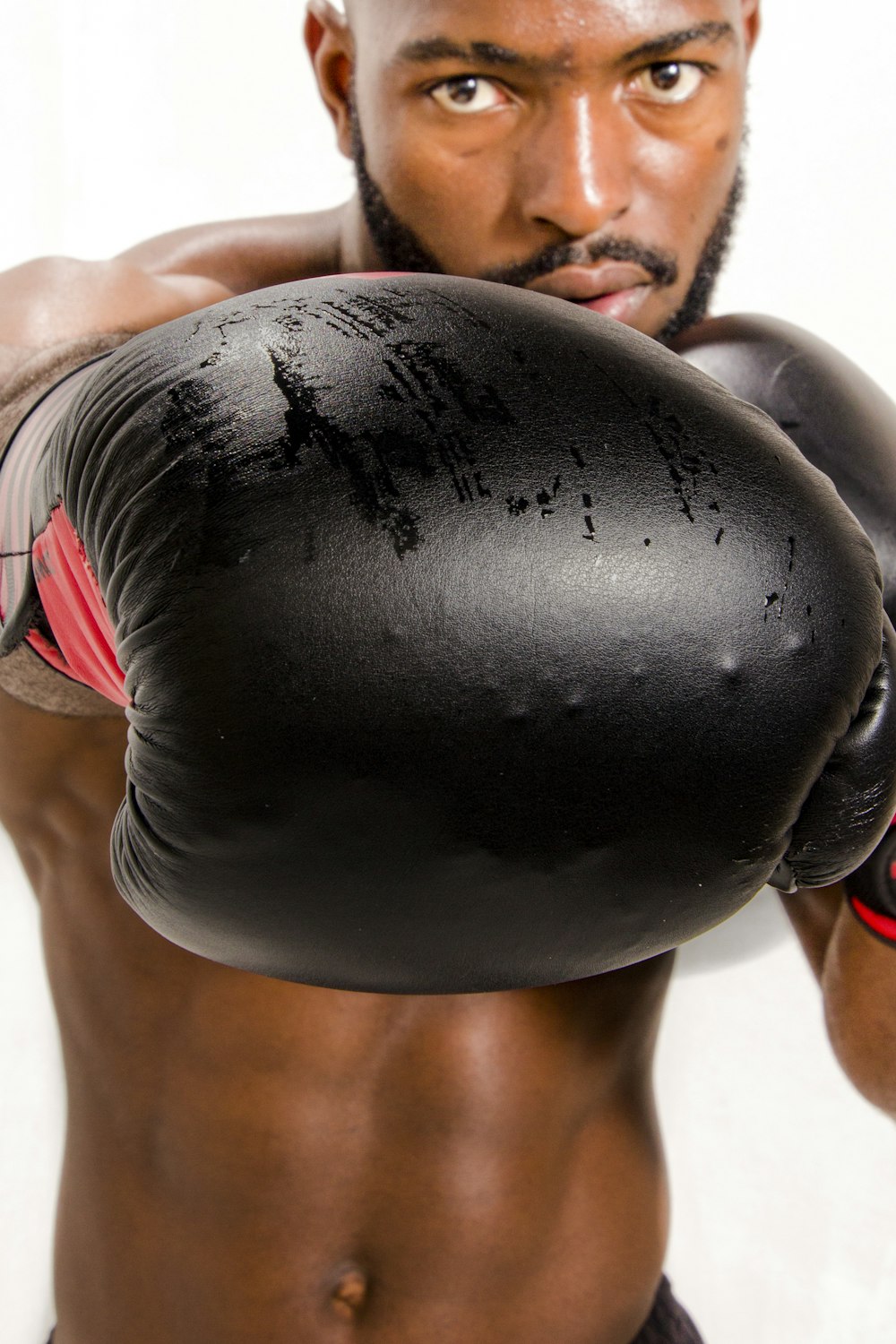 woman in white and red bikini lying on black leather boxing gloves