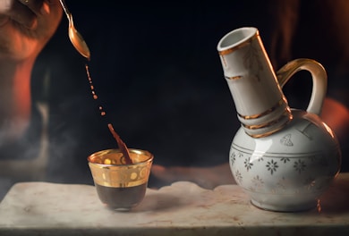 A hand pouring golden wild ginseng extract into a small cup
