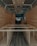 The interior of a van is under construction, featuring wooden paneling along the walls and ceiling. The floor has a dark wood finish, and the framework for what appears to be cabinetry or furniture is visible. Recessed lighting is installed in the ceiling.