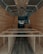 The interior of a van is under construction, featuring wooden paneling along the walls and ceiling. The floor has a dark wood finish, and the framework for what appears to be cabinetry or furniture is visible. Recessed lighting is installed in the ceiling.