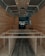 The interior of a van is under construction, featuring wooden paneling along the walls and ceiling. The floor has a dark wood finish, and the framework for what appears to be cabinetry or furniture is visible. Recessed lighting is installed in the ceiling.