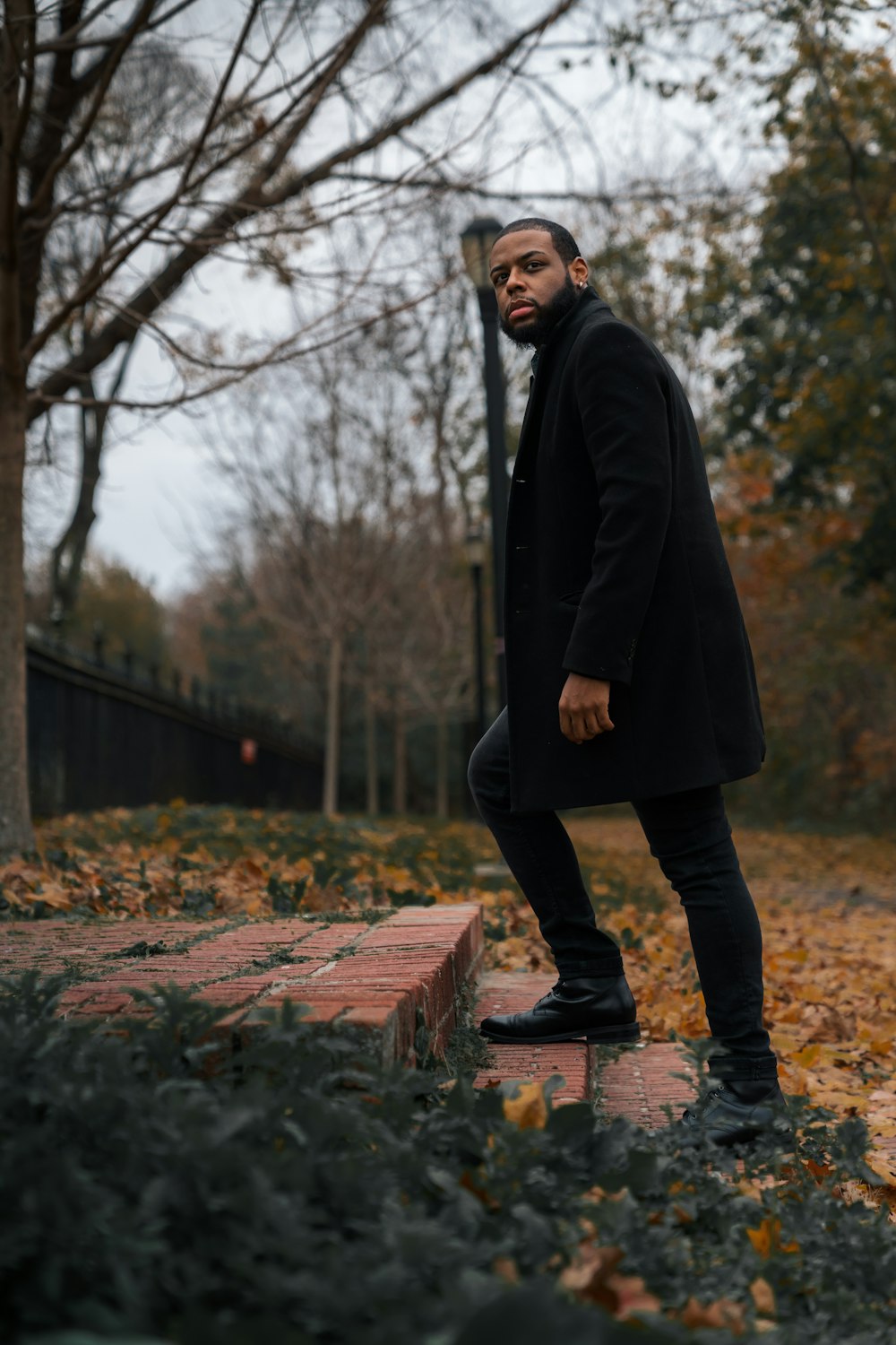 man in black coat standing on brown concrete brick during daytime