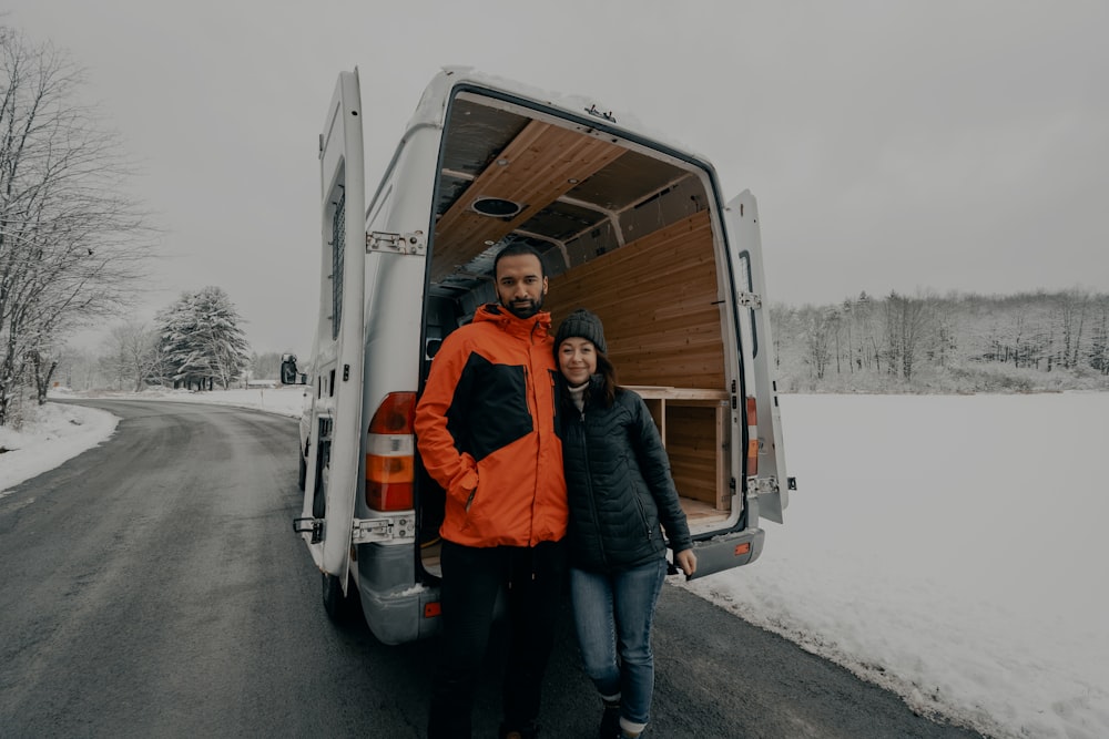 man in orange jacket standing beside woman in blue jacket