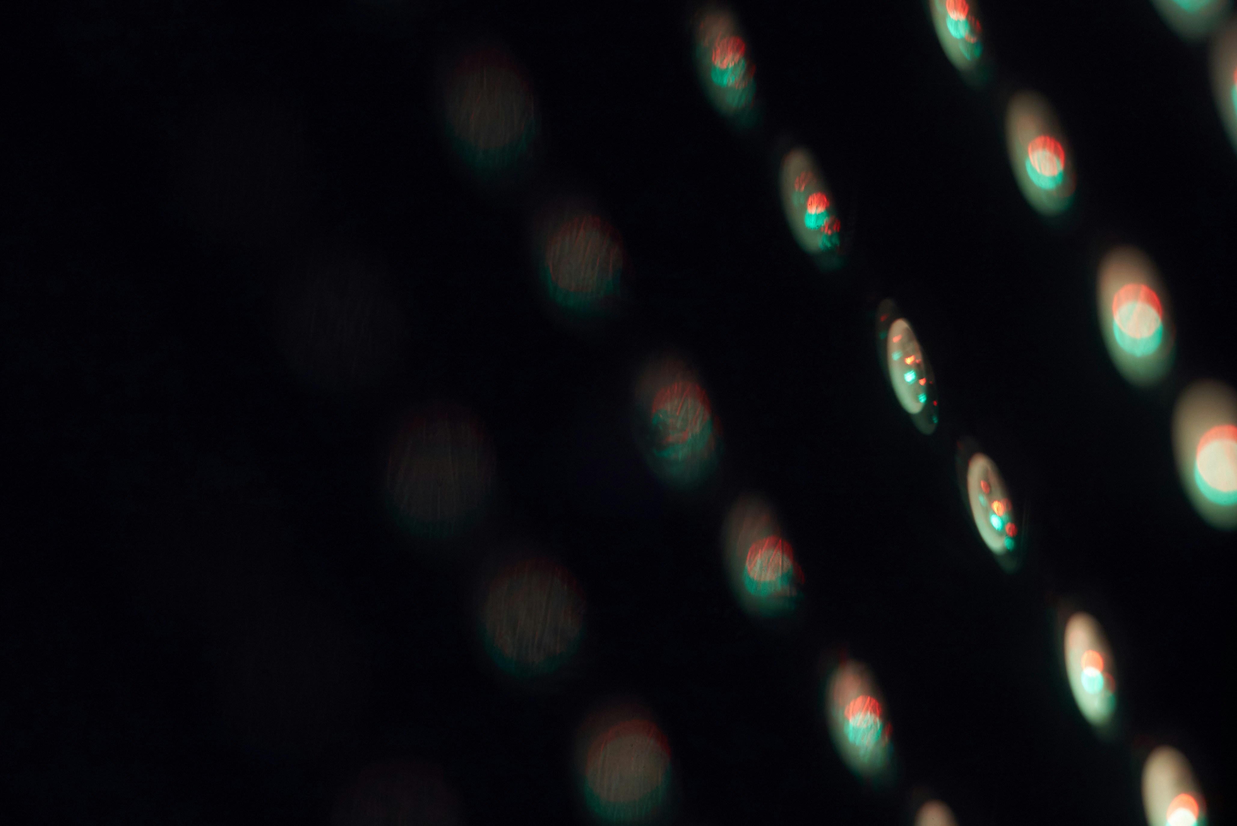 titanium smartwatch sensor array close up with green and infrared LEDs glowing