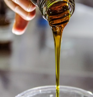 person holding clear drinking glass with brown liquid