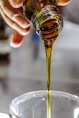 person holding clear drinking glass with brown liquid