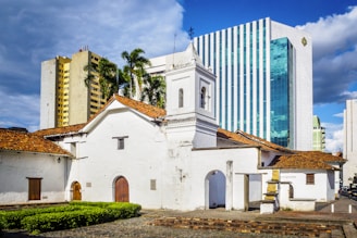 white and brown concrete building near green trees under blue sky during daytime