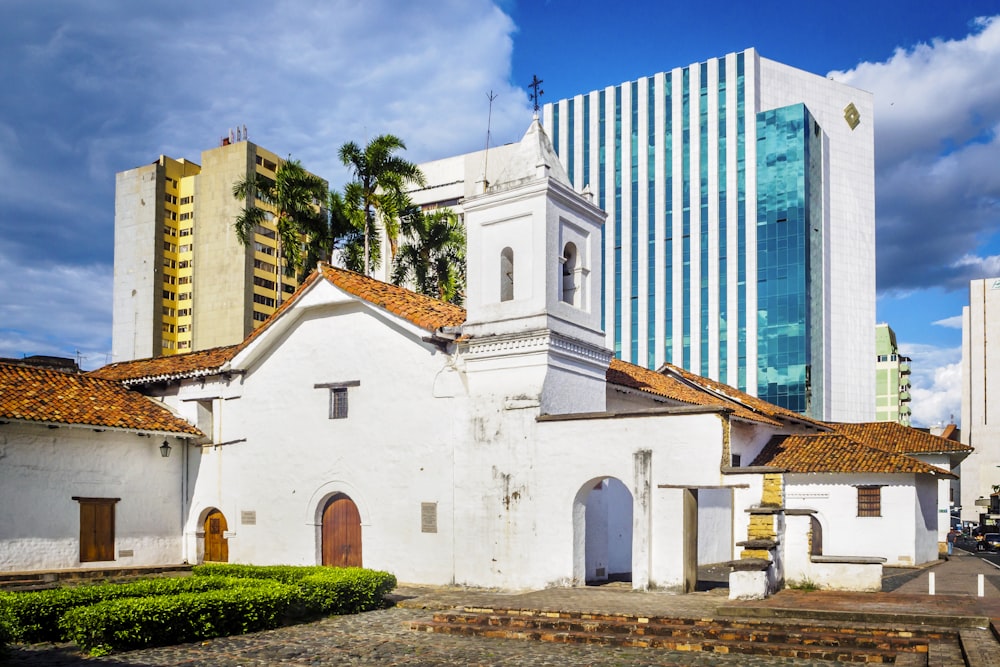 edifício de concreto branco e marrom perto de árvores verdes sob o céu azul durante o dia