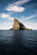 brown rock formation on sea under blue sky during daytime