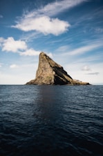 brown rock formation on sea under blue sky during daytime