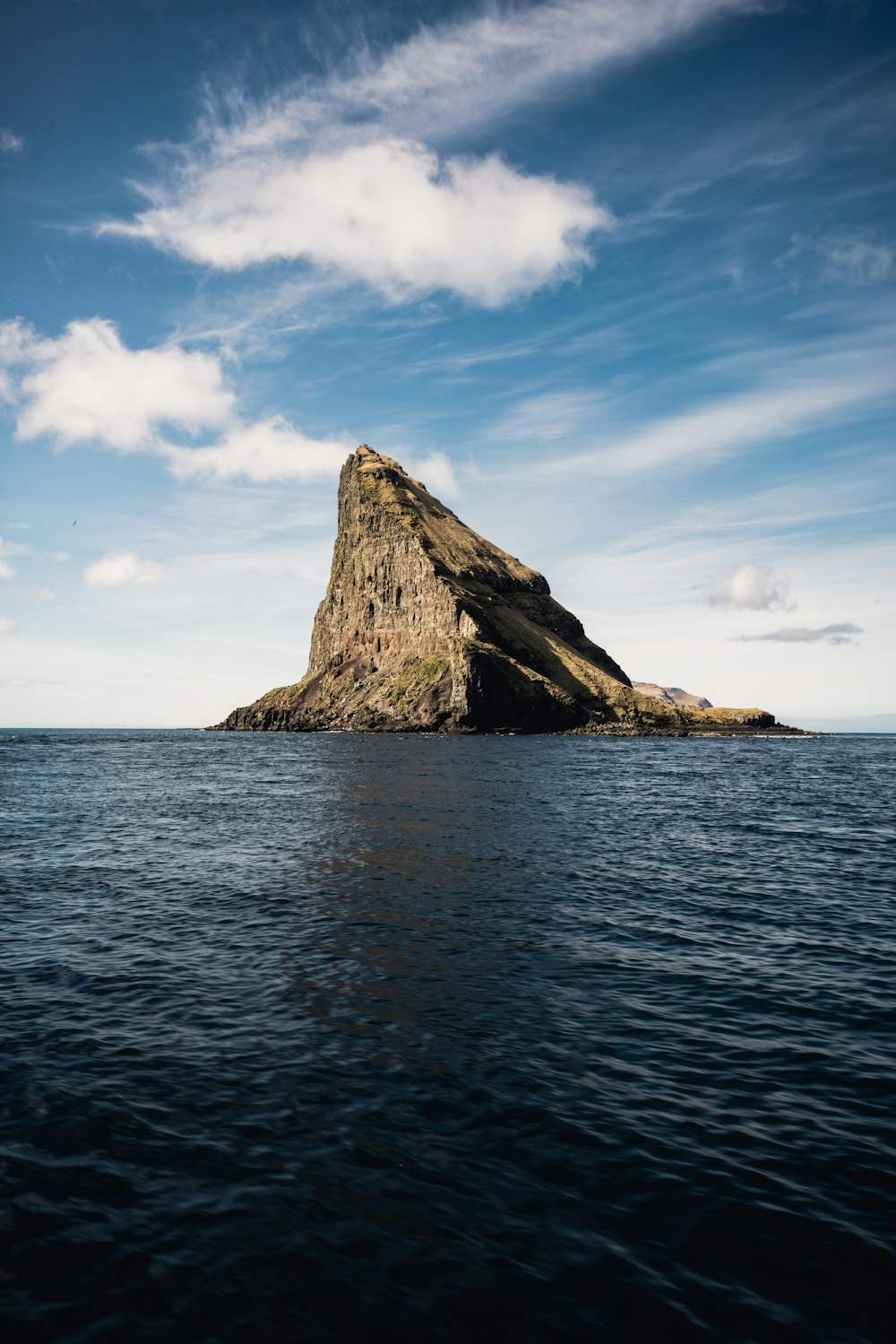 brown rock formation on sea under blue sky during daytime