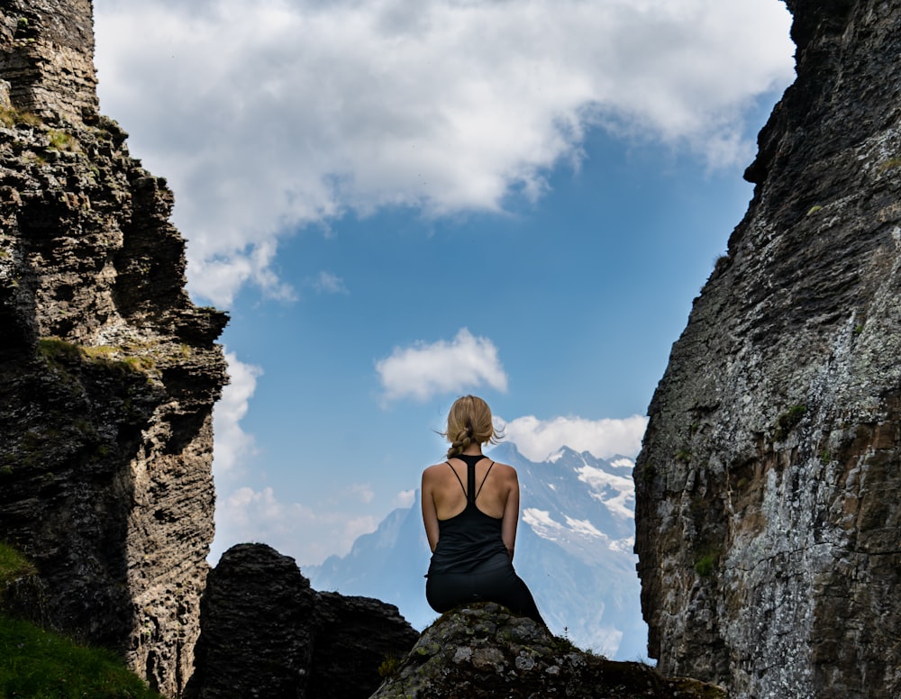 woman in black and white bikini top standing on rock formation under blue sky during daytime