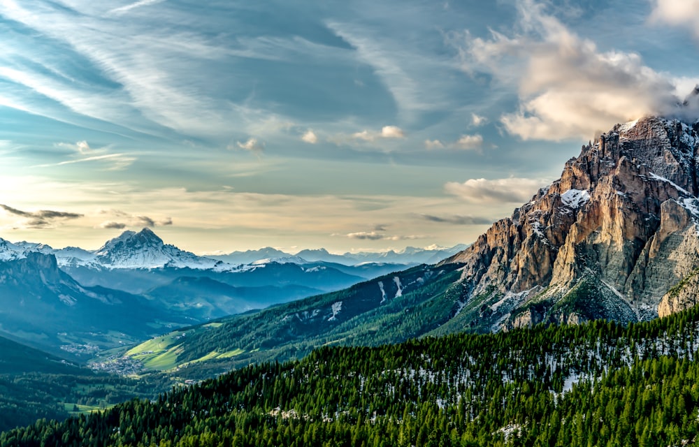 Grünes Grasfeld und Berge unter weißen Wolken und blauem Himmel tagsüber