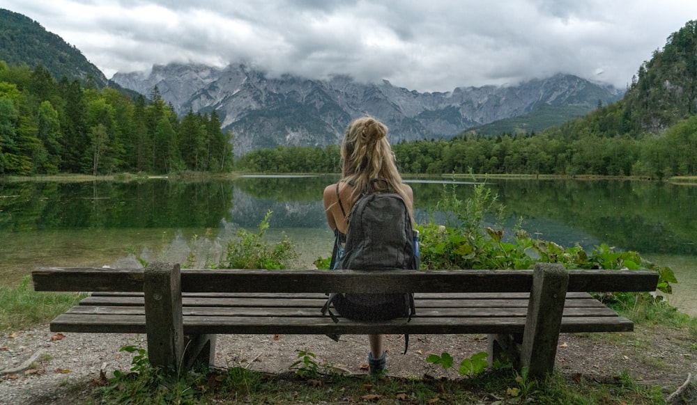 woman in green jacket sitting on brown wooden bench