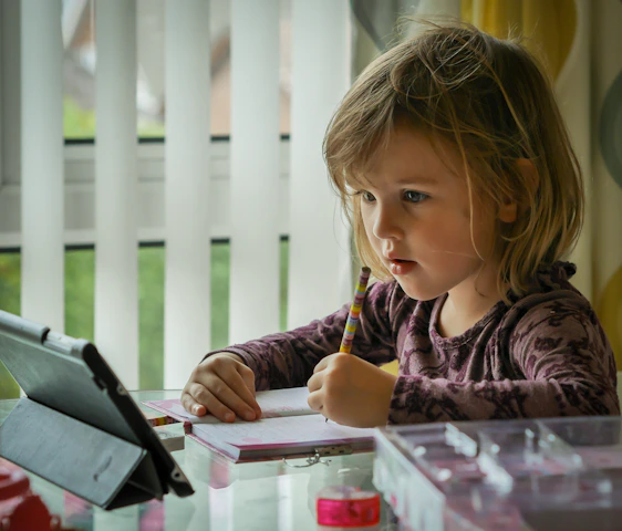 girl in purple and black long sleeve shirt holding black pen writing on white paper