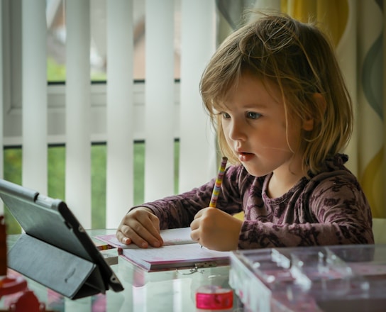 A calm study scene showing a child’s hands writing carefully in a spiral notebook under warm natural light.