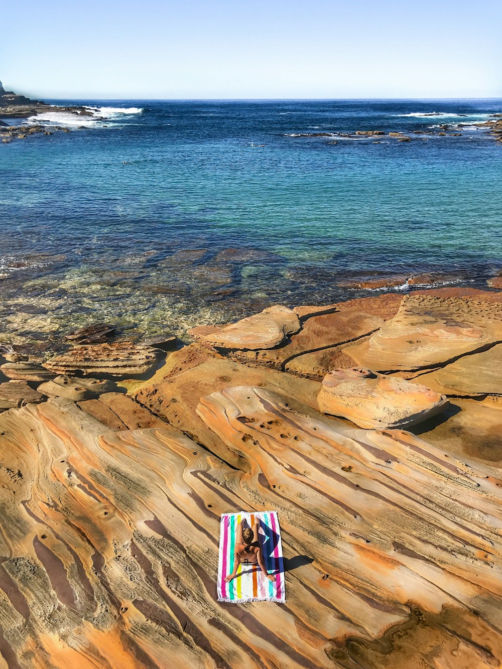 people standing on brown rock formation near body of water during daytime