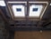 The image depicts the interior ceiling of a building under construction. There are wooden beams and a partial view of the roof structure. Two rectangular window installations are visible.
