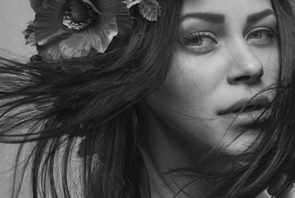 grayscale photo of woman with flower on her ear