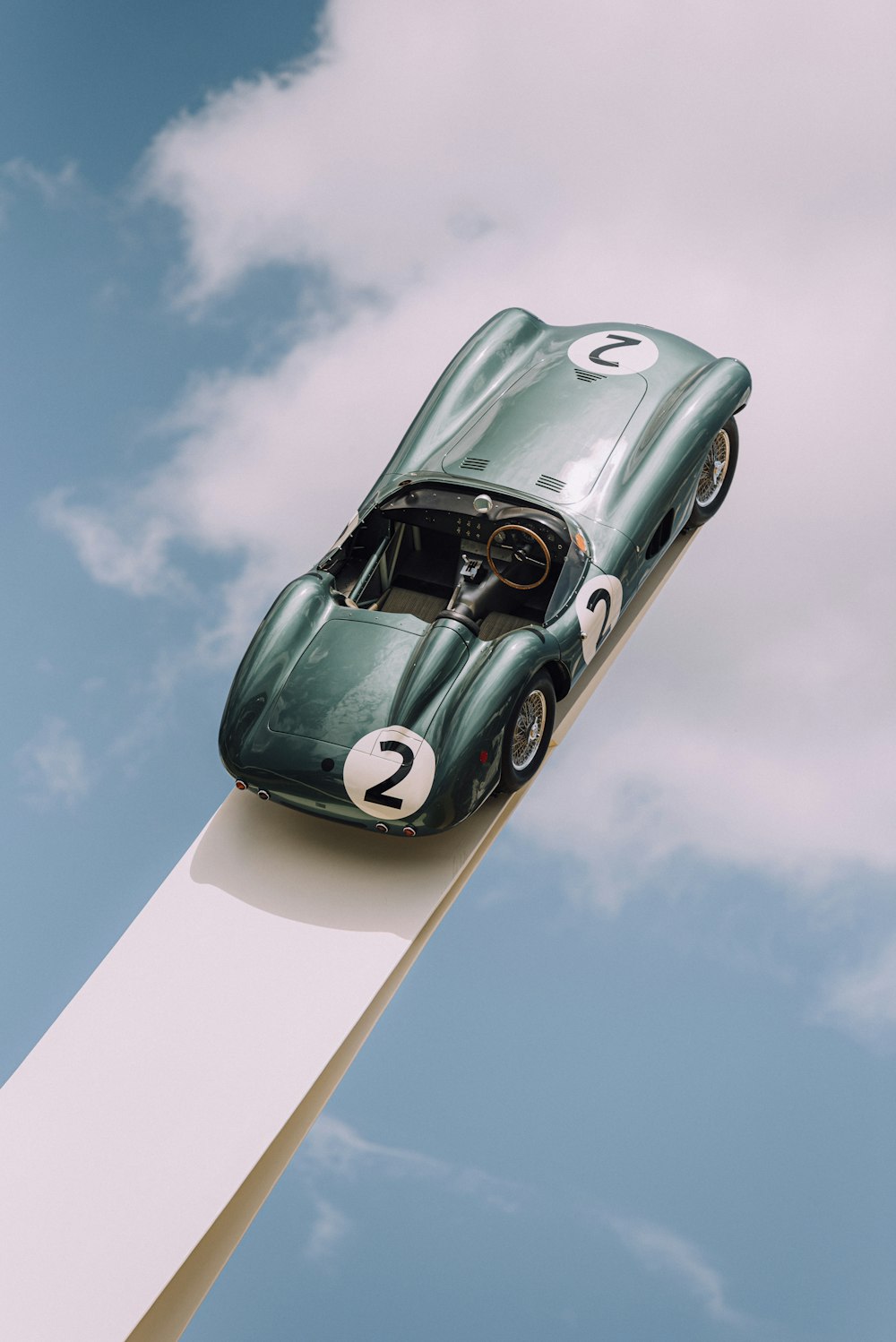 white and green volkswagen beetle on white wooden fence under blue sky during daytime