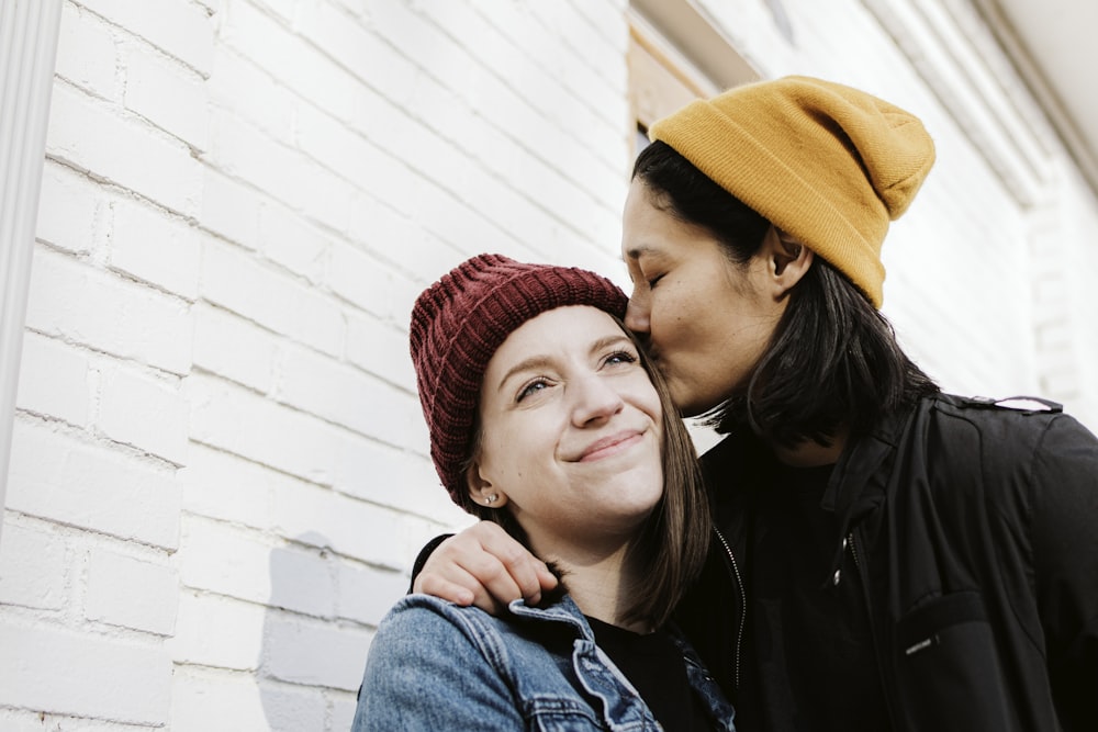 woman in blue denim jacket beside woman in red knit cap