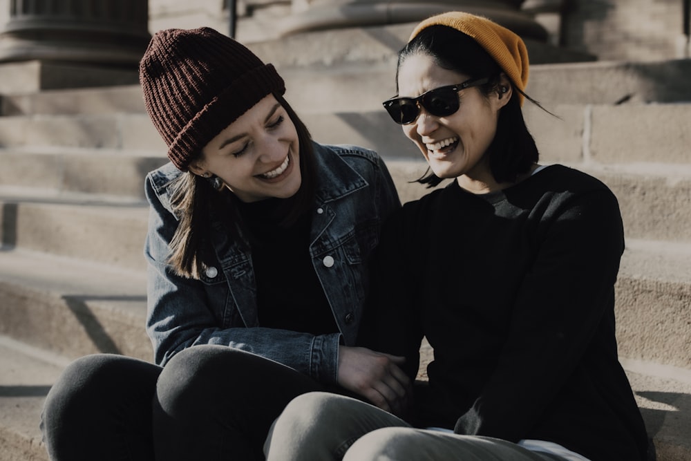 woman in black jacket and blue denim jeans sitting beside woman in black jacket