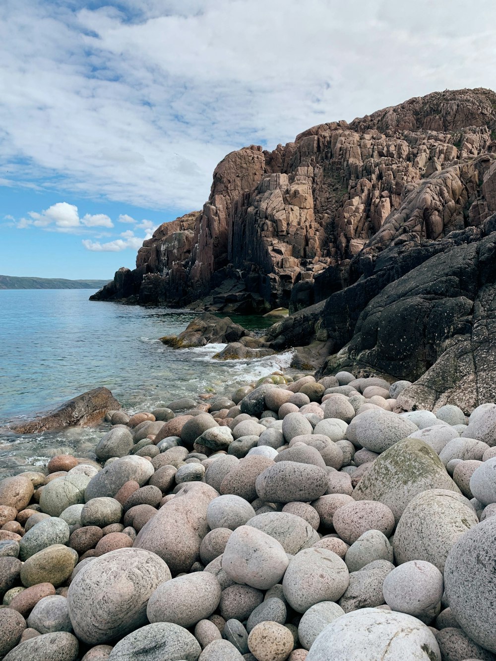 brown rocky mountain beside body of water during daytime