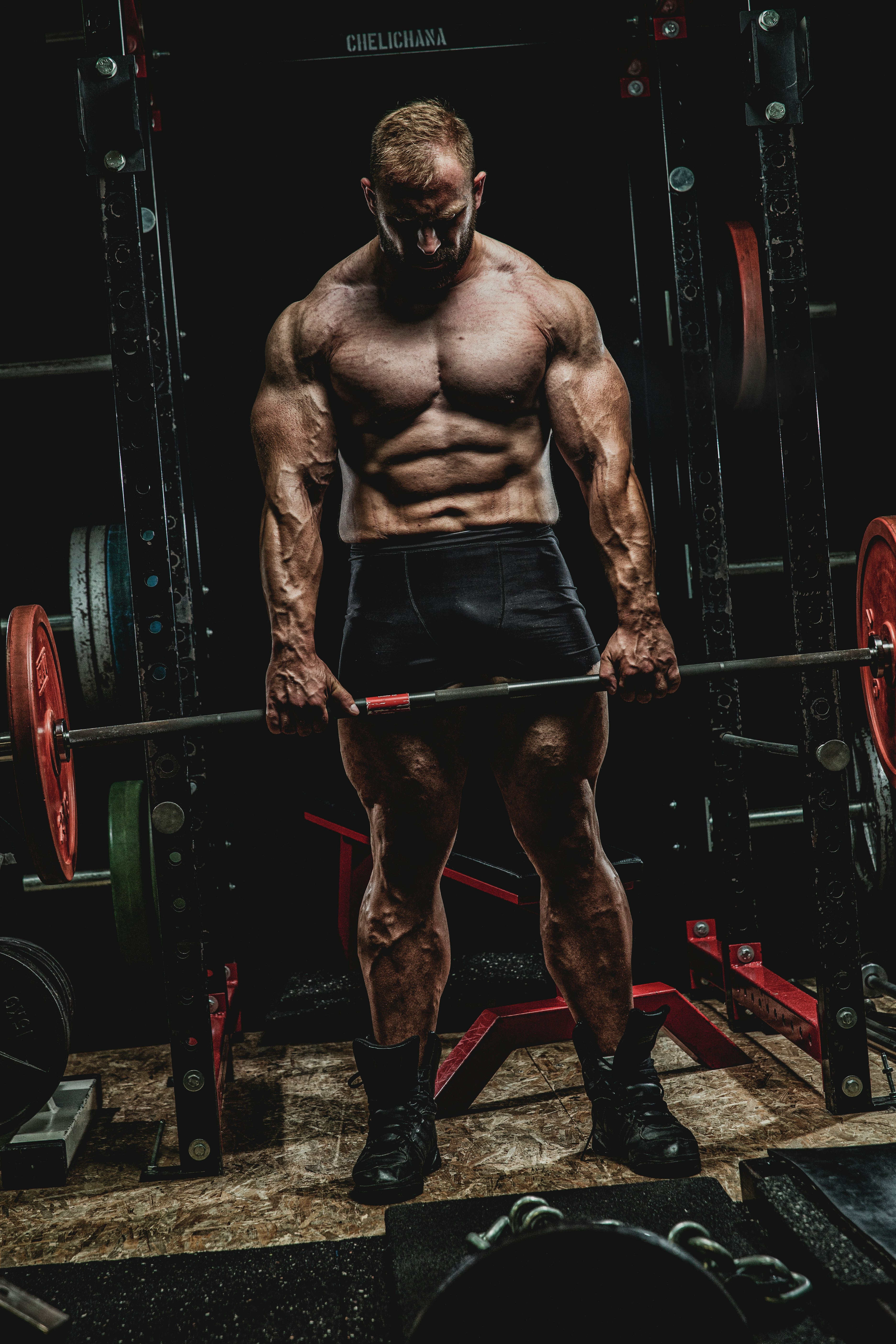 topless man in black shorts standing on black and red exercise equipment