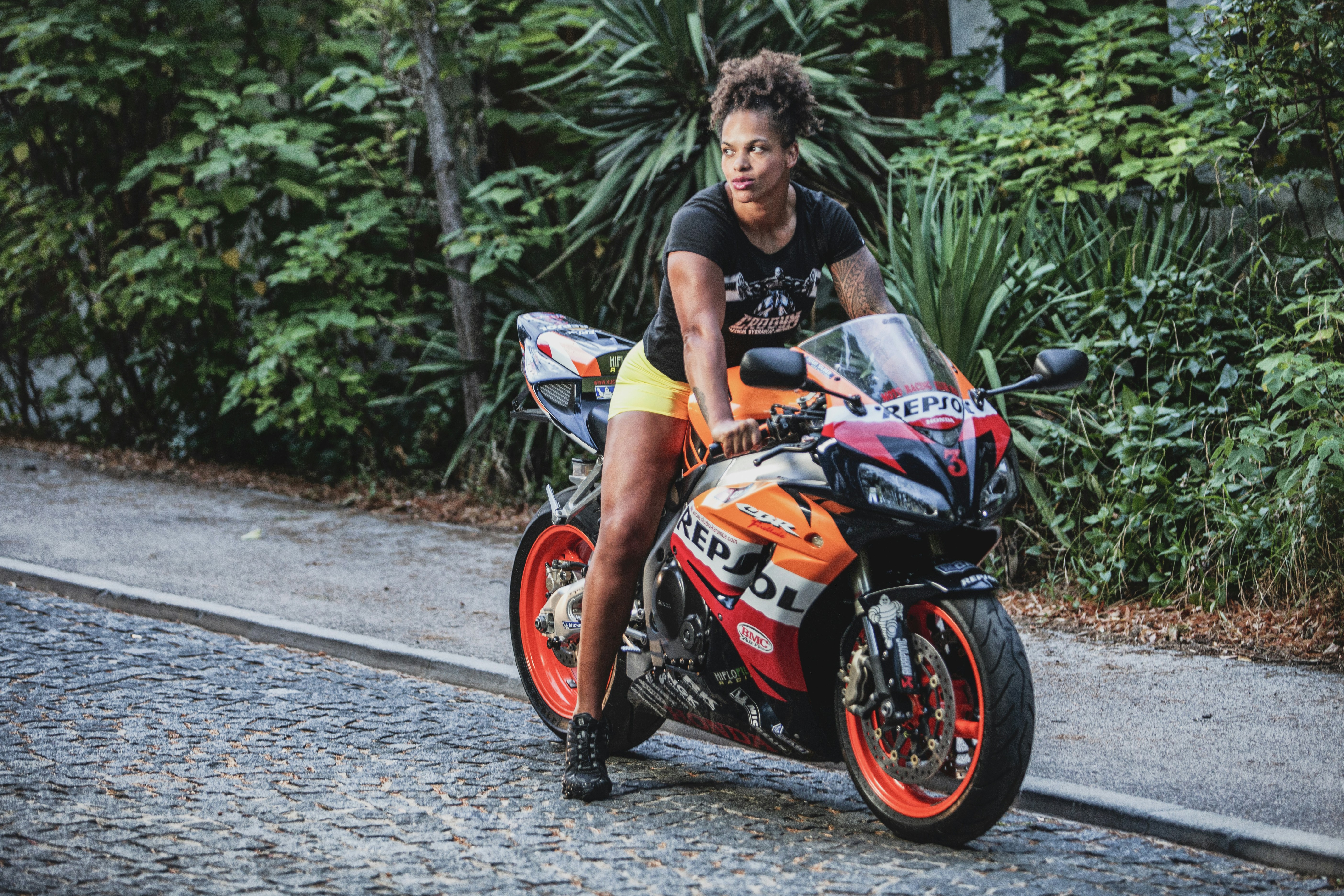 man in black tank top riding orange and black honda sports bike 