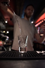 A bartender placing clear ice cubes into a cocktail glass.