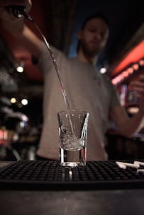A bartender placing a large, clear ice block into a glass, highlighting its purity and clarity.