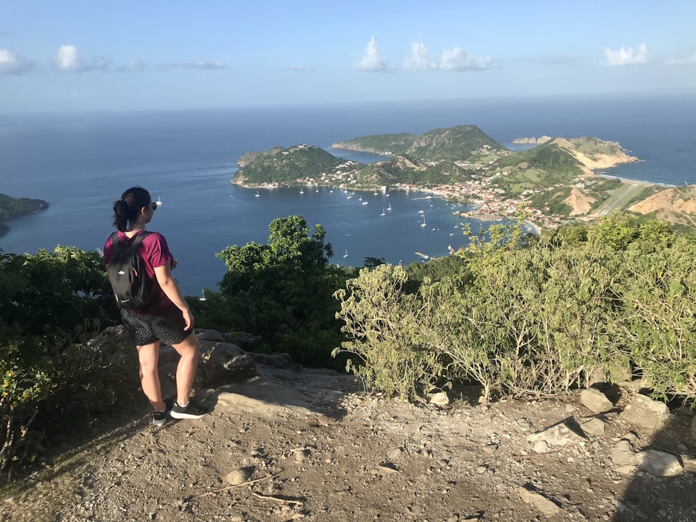 man in black t-shirt and black shorts sitting on rock near body of water during