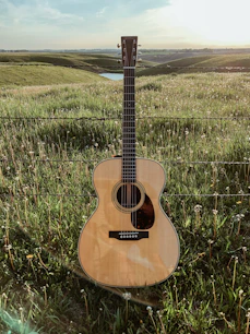 brown acoustic guitar on green grass field during daytime