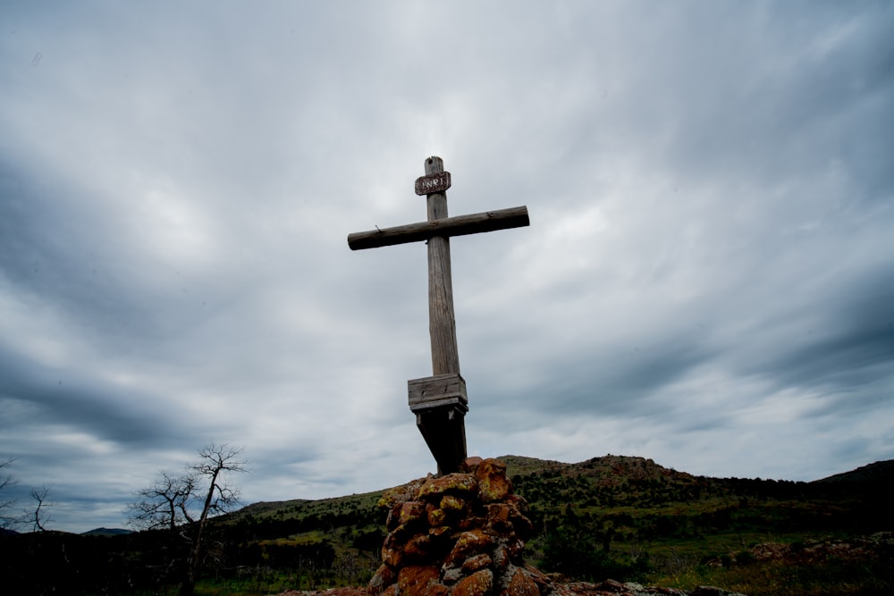 brown wooden cross on brown rock under white clouds during daytime