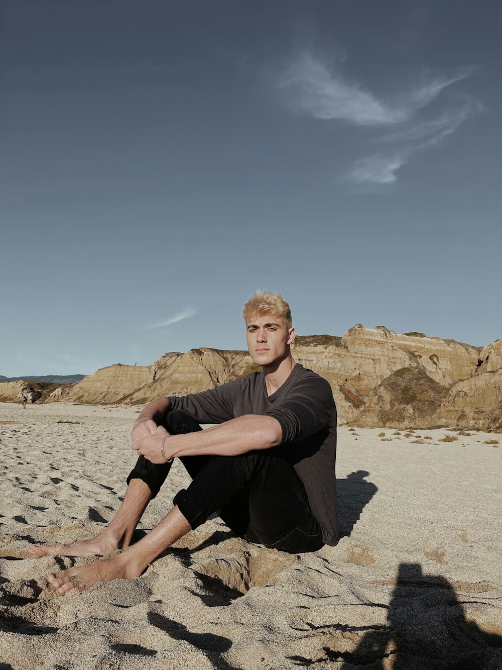 man in black crew neck t-shirt sitting on brown rock during daytime