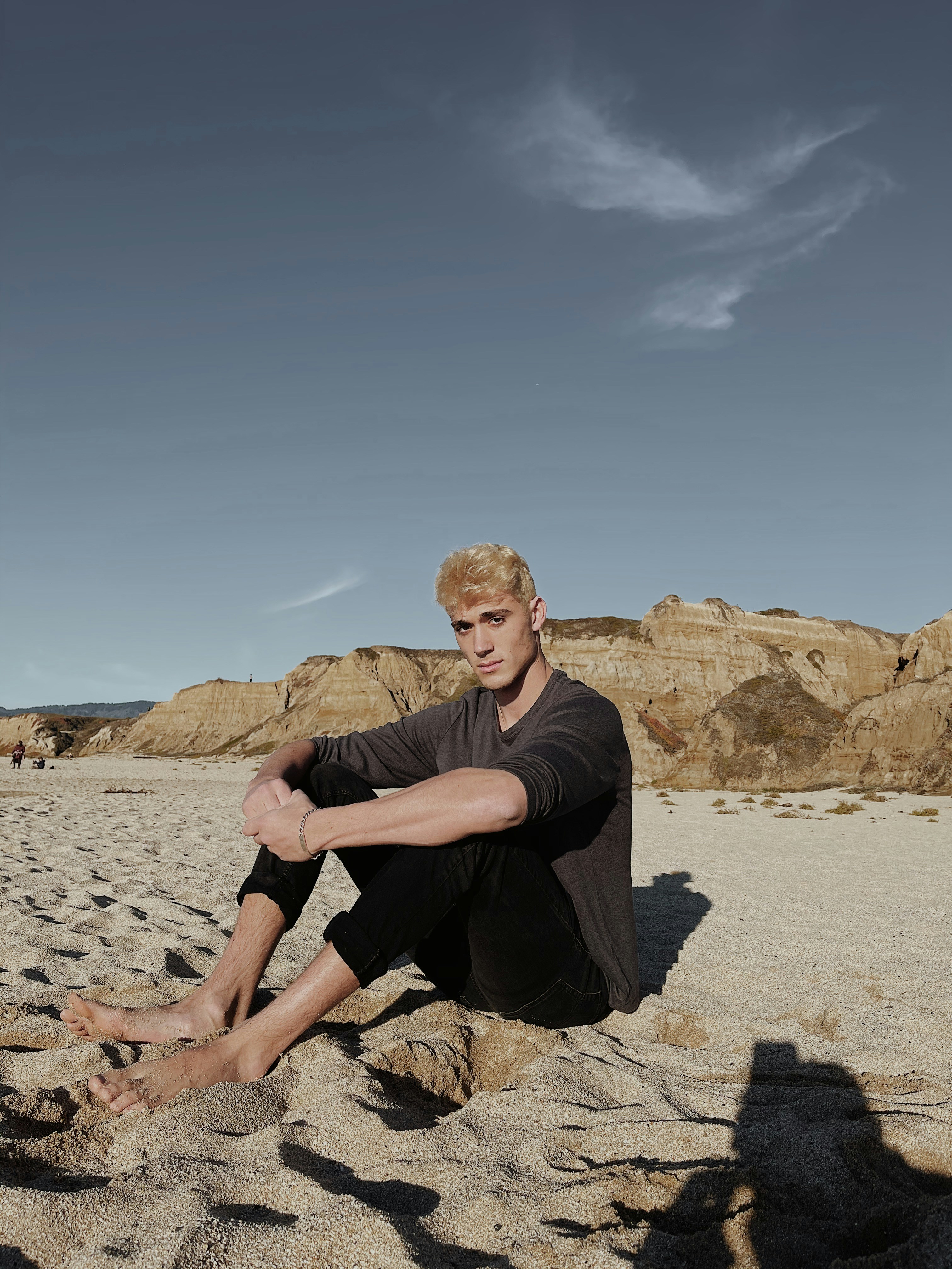 man in black crew neck t-shirt sitting on brown rock during daytime