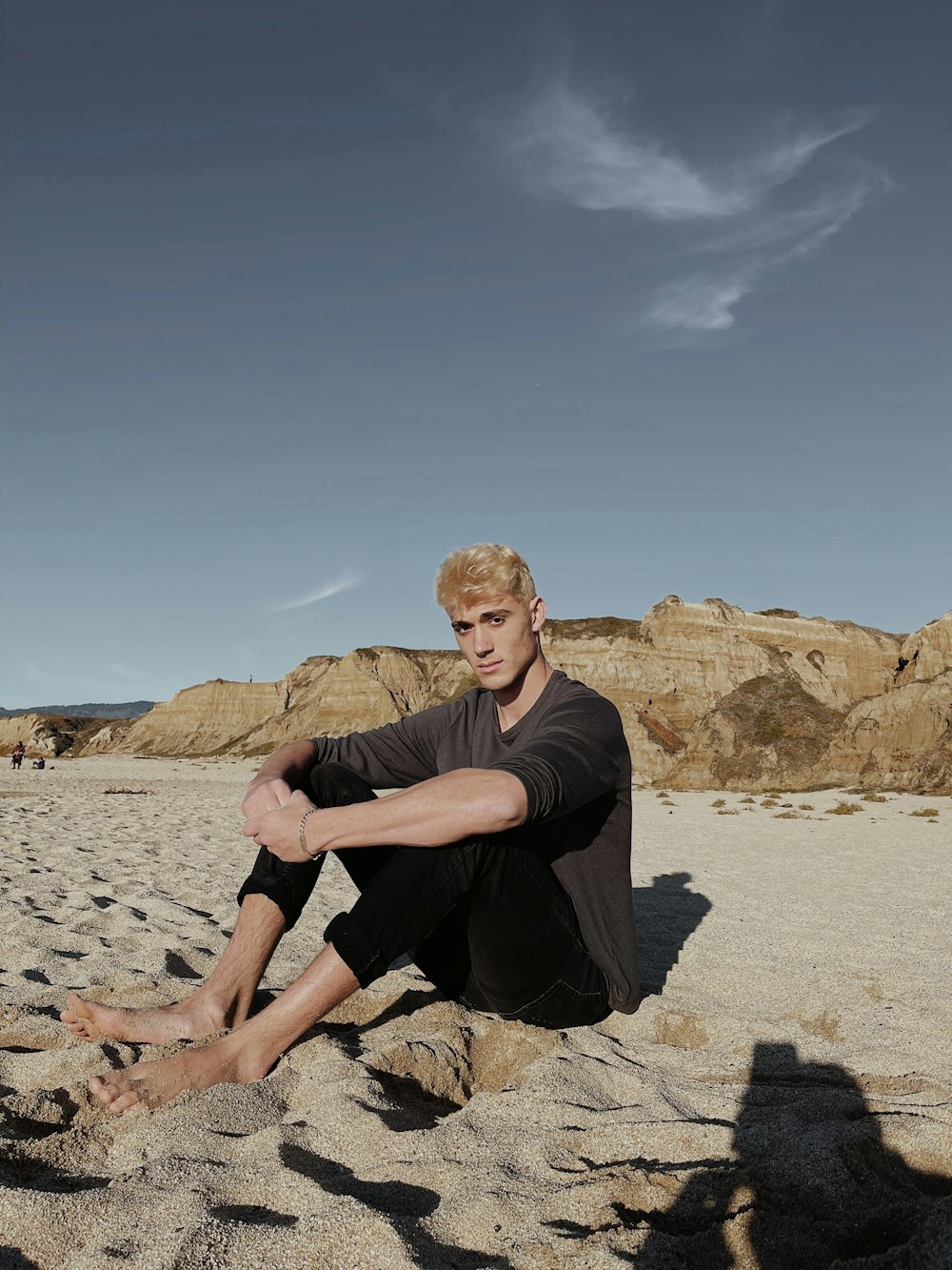 man in black crew neck t-shirt sitting on brown rock during daytime