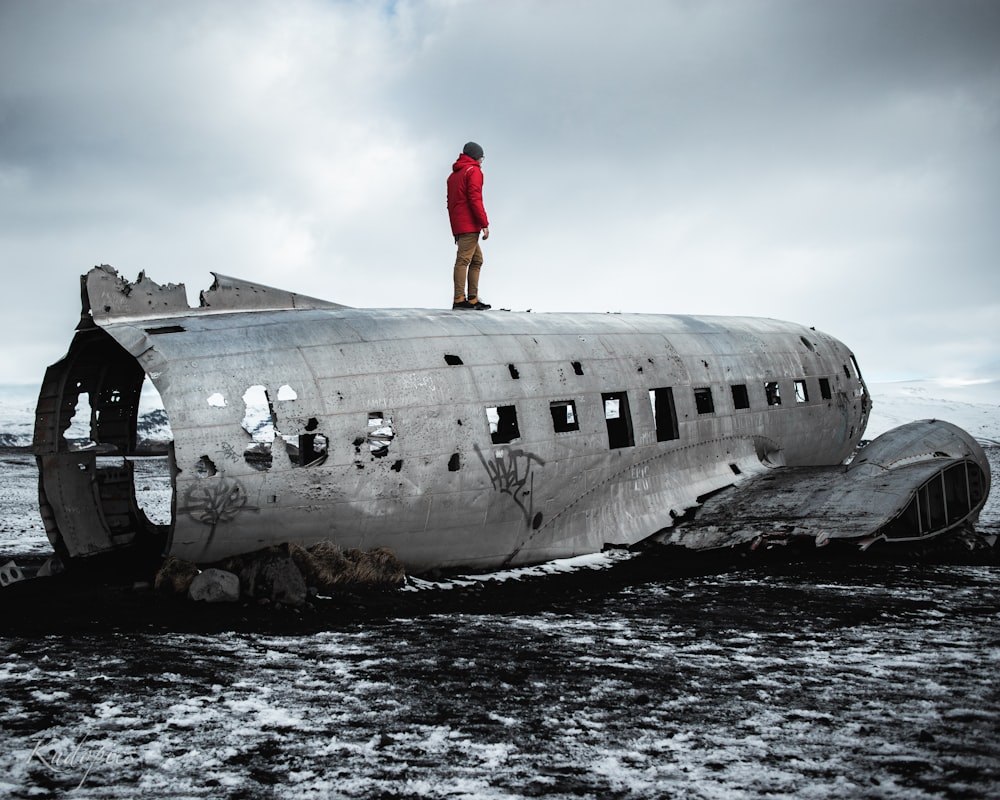 man in red jacket standing on white airplane