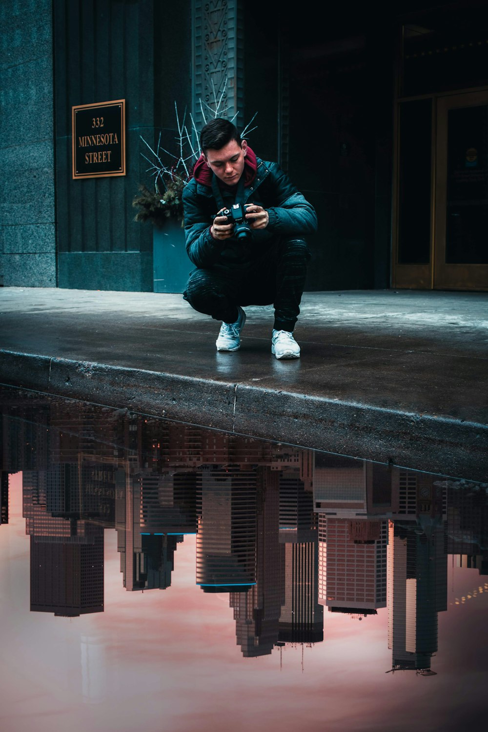 man in blue jacket and black pants sitting on concrete bench