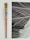 An aged paintbrush with a colorful, paint-splattered handle sits beside an abstract black and white artwork, featuring dynamic white lines crossing over a dark background.